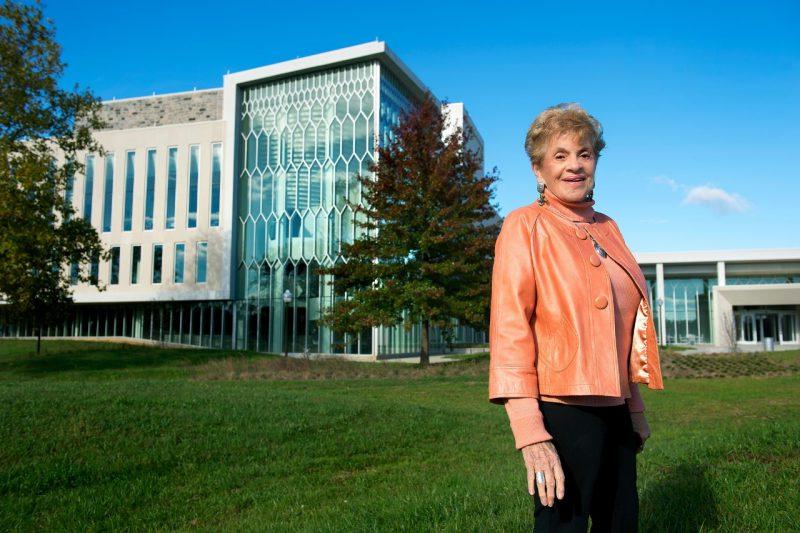 A woman stands in front of a large building on Virginia Tech's Blacksburg campus